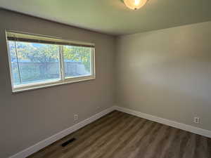 Spare room featuring baseboards and dark wood-type flooring