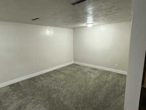 Finished below grade area featuring a textured ceiling and dark carpet