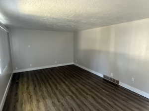 Empty room with dark wood-style floors and a textured ceiling