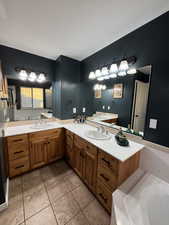 Full bath with double vanity, a garden tub, and light tile patterned flooring