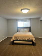 Bedroom featuring dark carpet and a textured ceiling