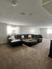 Carpeted living area featuring a textured ceiling and baseboards
