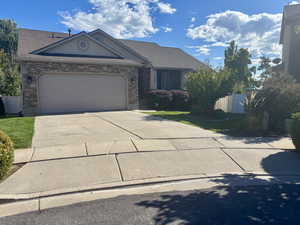 View of front of house featuring stone siding, an attached garage, and driveway