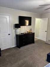 Bedroom featuring ornamental molding, dark carpet, and a ceiling fan