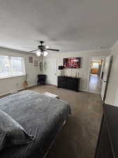 Carpeted bedroom featuring a textured ceiling and a ceiling fan