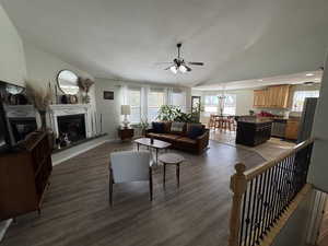 Living area featuring vaulted ceiling, light wood-style floors, healthy amount of natural light, a glass covered fireplace, and a textured ceiling