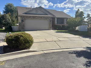 View of front of house with concrete driveway, a garage, stone siding, and stucco siding