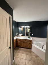 Bathroom featuring a textured ceiling, double vanity, a garden tub, and light tile patterned flooring