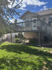 Rear view of property featuring a deck, stucco siding, and stairs