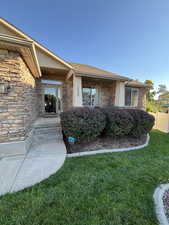 Doorway to property featuring stone siding and roof with shingles