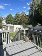 Wooden terrace with a storage unit and a fenced backyard