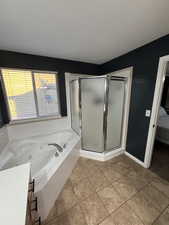 Ensuite bathroom with a jetted tub, a stall shower, and light tile patterned floors