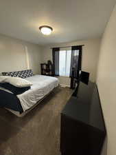 Bedroom featuring dark colored carpet and a textured ceiling