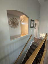Stairway with wood finished floors, arched walkways, and a towering ceiling