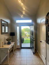 Foyer featuring vaulted ceiling, healthy amount of natural light, and light tile patterned floors