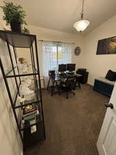 Office area featuring dark carpet and lofted ceiling