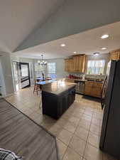 Kitchen with a textured ceiling, freestanding refrigerator, decorative light fixtures, a breakfast bar area, and dark stone countertops