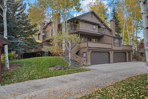 View of front facade featuring an attached garage, a balcony, stairway, concrete driveway, and a front yard