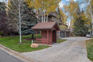 View of front of property with a front yard, roof with shingles, and a detached garage