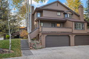 View of front of house featuring stairway, a chimney, a garage, and driveway