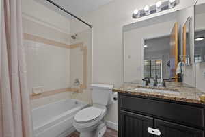 Full bathroom featuring shower / bathtub combination with curtain, vanity, and dark wood-style flooring