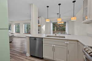 Kitchen featuring glass insert cabinets, appliances with stainless steel finishes, pendant lighting, light stone counters, and open floor plan