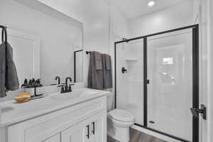 Full bath featuring a stall shower, vanity, dark wood-style floors, and recessed lighting