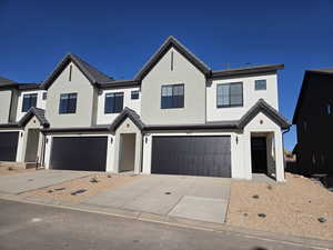 Modern farmhouse with concrete driveway, stucco siding, and a garage