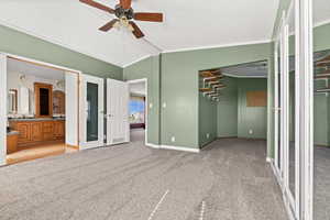 Unfurnished bedroom featuring lofted ceiling, light colored carpet, a textured ceiling, connected bathroom, and ceiling fan