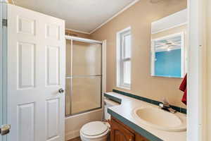 Full bath featuring vanity, enclosed tub / shower combo, a textured ceiling, and crown molding