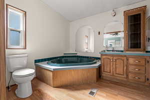 Full bath with vanity, a garden tub, and light wood-type flooring