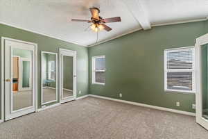 Unfurnished bedroom featuring multiple closets, a textured ceiling, carpet flooring, crown molding, and ceiling fan