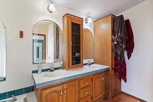Full bathroom featuring a textured ceiling, double vanity, and wood finished floors