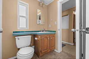 Half bathroom with vanity, tile patterned flooring, and crown molding