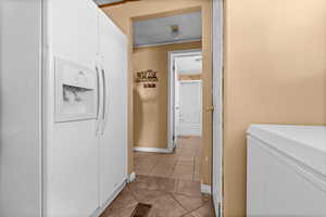 Laundry area with light tile patterned floors and a textured ceiling