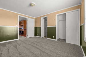 Unfurnished bedroom featuring ornamental molding, carpet floors, a closet, and a textured ceiling