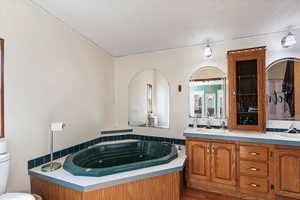 Full bathroom featuring double vanity, a tub with jets, and a textured ceiling