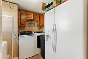 Laundry room with a textured ceiling, light tile patterned floors, washing machine and dryer, and cabinet space