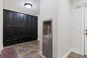 Mudroom with a textured ceiling and stone finish flooring