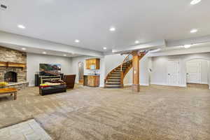 Living room featuring recessed lighting, light carpet, a fireplace, stairway, and bar
