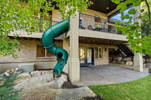 Rear view of house featuring a patio, brick siding, and a balcony
