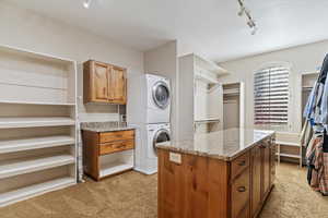 Master Bedroom Walk in closet featuring light colored carpet and stacked washer and clothes dryer