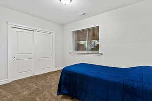 Carpeted bedroom with a textured ceiling and a closet