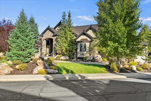 View of front of house with stone siding and a front lawn