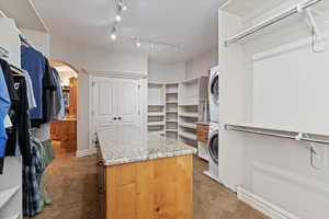 Master Bedroom Walk in closet with arched walkways, light colored carpet, and stacked washer / dryer