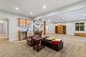 Living room featuring light colored carpet, arched walkways, recessed lighting, and stairway