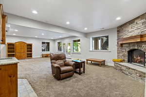 Living room with light carpet, a stone fireplace, and recessed lighting