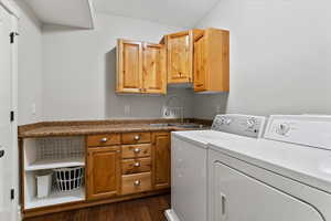 Washroom with cabinet space, washer and clothes dryer, and dark wood-style flooring