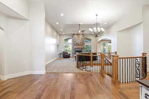 Hallway with an upstairs landing, a chandelier, arched walkways, light wood-style flooring, and recessed lighting