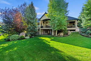 Rear view of property with a lawn and a balcony